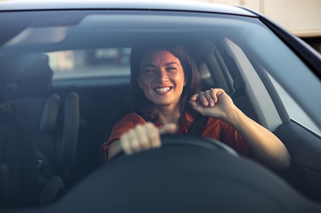 Mulher de negócios feliz viajando com seu carro pela cidade Bela jovem sorridente feliz dirigindo seu carro novo no pôr do sol