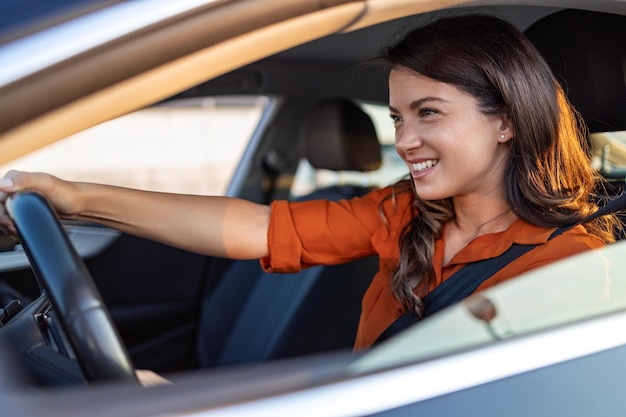 Foto mulher de negócios feliz viajando com seu carro pela cidade linda jovem feliz e sorridente dirigindo seu carro novo ao pôr do sol