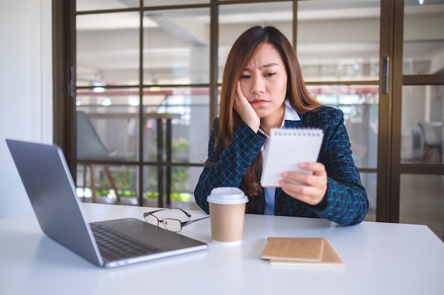 Mulher de negócios fica estressada enquanto trabalha e olha um documento no escritório