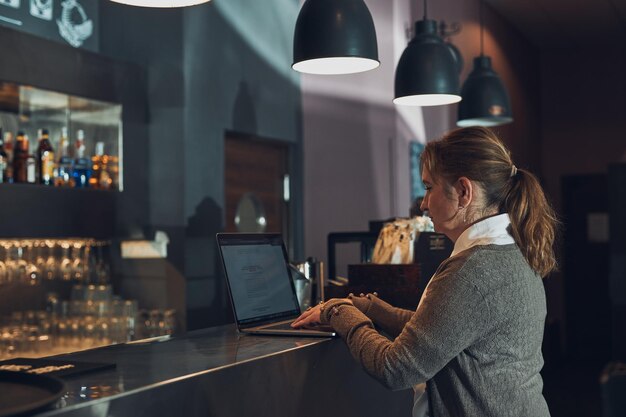 Foto mulher de negócios focada trabalhando remotamente em seu computador portátil considera gerenciar seu trabalho