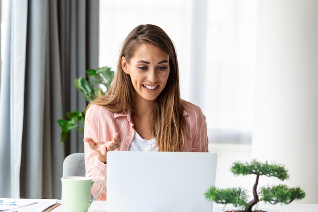 Mulher de negócios focada usando laptop em casa olhando para a tela conversando lendo ou escrevendo e-mail sentada no sofá aluna fazendo lição de casa trabalhando no projeto de pesquisa online