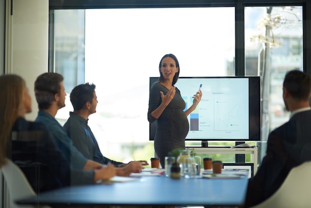 Mulher de negócios grávida e apresentação de inicialização em uma oficina de trabalho em equipe com fala e comunicação gerente de gravidez feminina e aprendizado da empresa com funcionários e chefe com estratégia de gráfico de vendas