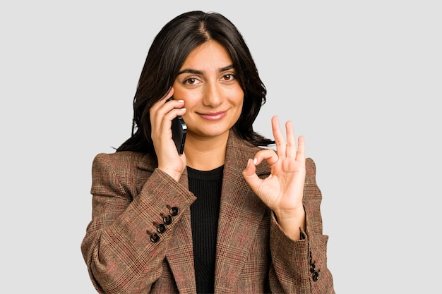 Mulher de negócios indiana jovem ligando com telefone móvel isolado
