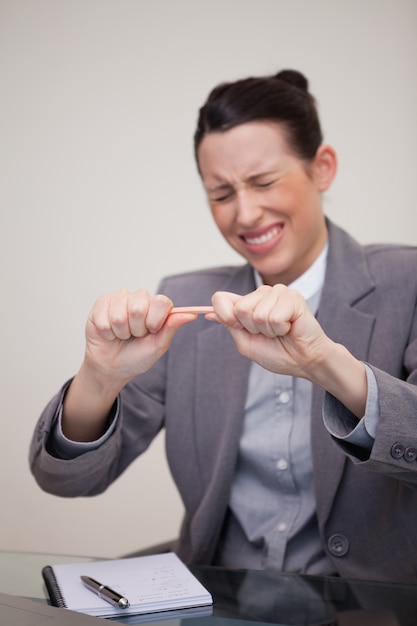 Mulher de negócios irritada tentando quebrar o lápis