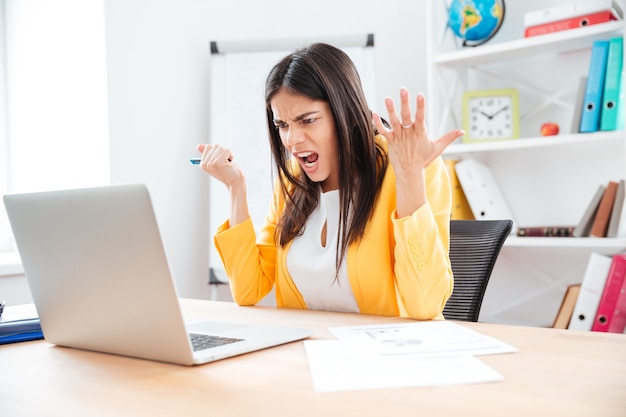 Mulher de negócios irritada usando laptop no escritório