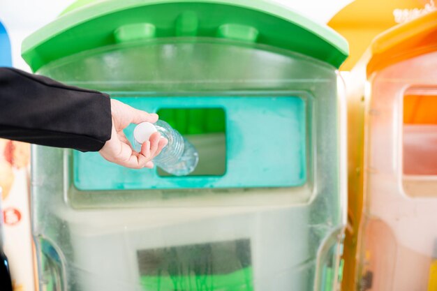 Mulher de negócios jogando água de garrafa de plástico vazia no lixo reciclável