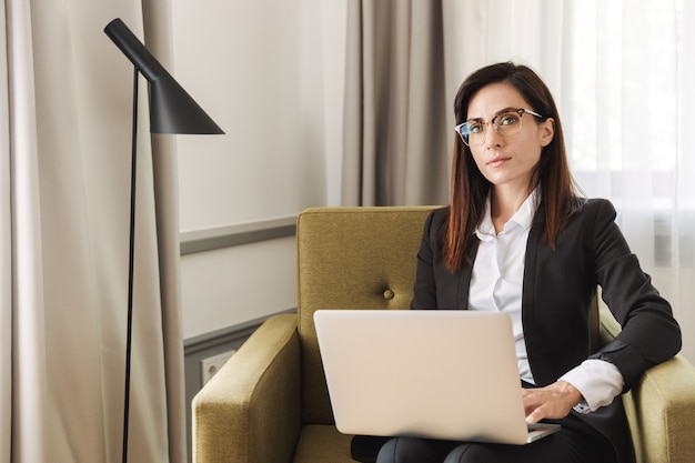 mulher de negócios jovem bonita com roupas de uso formal dentro de casa em casa trabalhar com o computador portátil.