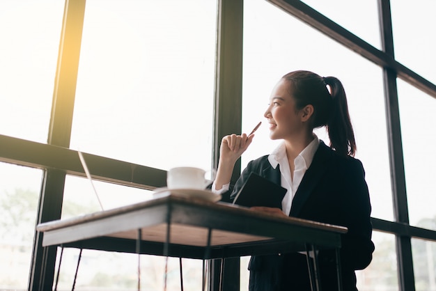 Foto mulher de negócios jovem bonita sentada à mesa e tomando notas