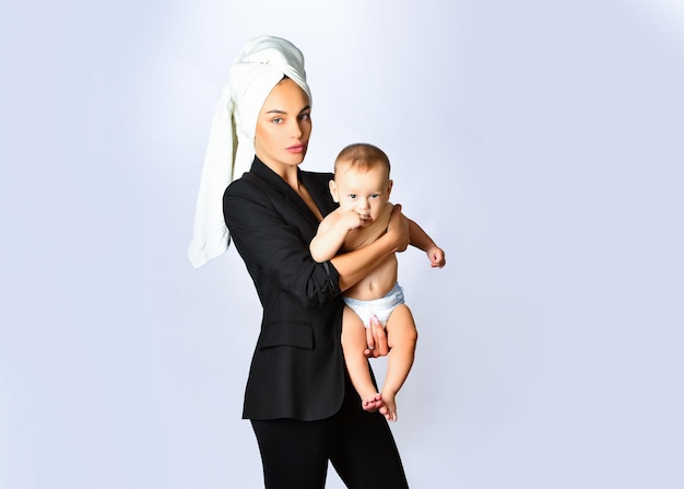 Mulher de negócios jovem carregando seu filho com toalha na cabeça mãe feliz segurando um bebê nos braços e beijando linda mulher segurando um bebê recém-nascido nos braços