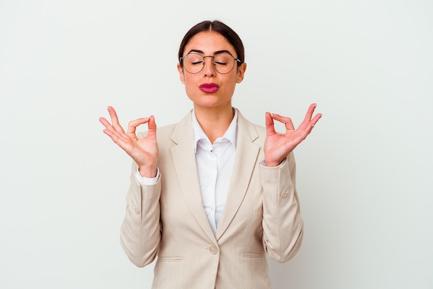 Mulher de negócios jovem caucasiana isolada no fundo branco relaxa após um árduo dia de trabalho, ela está realizando ioga.