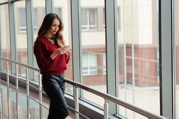 Mulher de negócios jovem com uma camisola vermelha com telefone móvel.