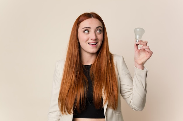 Mulher de negócios jovem de cabelo vermelho segurando uma lâmpada novo conceito de ideia