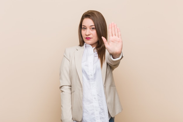 Mulher de negócios jovem de pé com a mão estendida, mostrando o sinal de stop, impedindo-o.