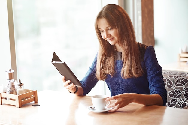 Foto mulher de negócios jovem em um café lendo um ebook e bebendo café