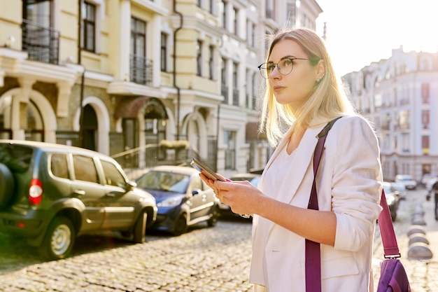 Mulher de negócios jovem na cidade usando tablet digital linda mulher sorridente na jaqueta branca com óculos olhando para o fundo do estilo urbano do espaço da cópia do monitor do tablet