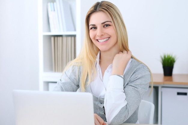 Mulher de negócios jovem ou estudante sentada no local de trabalho do escritório com computador portátil. Conceito de negócio em casa.