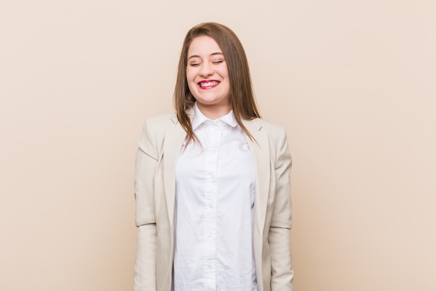 Mulher de negócios jovem ri e fecha os olhos, sente-se relaxada e feliz.