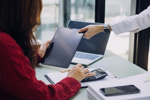 Mulher de negócios jovem sentada no escritório à mesa e usando smartphone Na mesa está o laptop e o tablet na tela gráficos e gráficos Mulher analisando dados Estudante aprendendo online