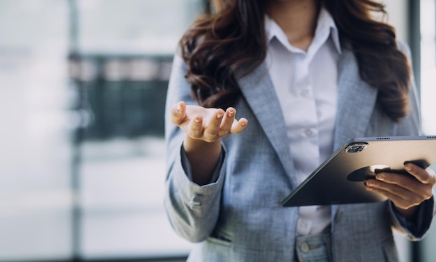 Mulher de negócios jovem sentada no escritório à mesa e usando smartphone Na mesa está o laptop e o tablet na tela gráficos e gráficos Mulher analisando dados Estudante aprendendo online