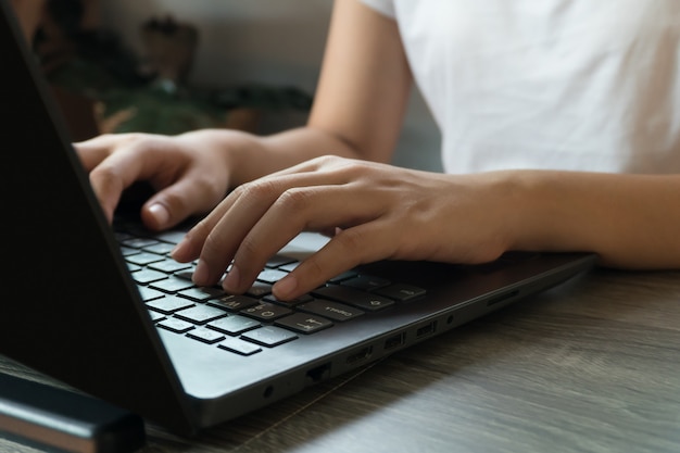 Mulher de negócios jovem sentado à mesa com o laptop e tomar notas no caderno.