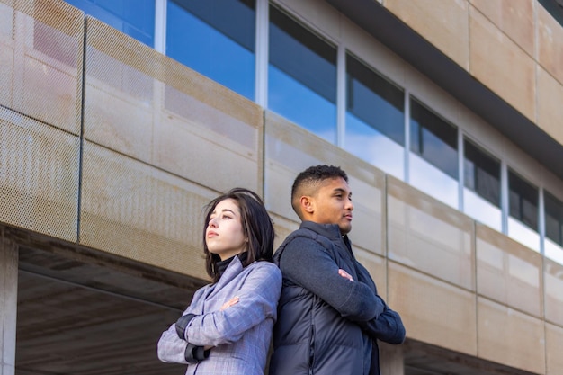 Mulher de negócios latino e homem de costas com os braços cruzados na rua seriedade e compromisso dos jovens para iniciar um negócio