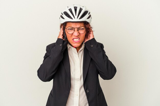 Mulher de negócios latinos de meia-idade usando um capacete de bicicleta isolado no fundo branco, cobrindo as orelhas com as mãos.