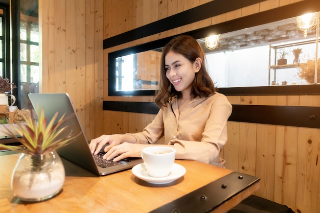 Mulher de negócios linda está trabalhando com o laptop na cafeteria