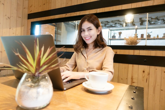 Mulher de negócios linda está trabalhando com seu laptop na cafeteria