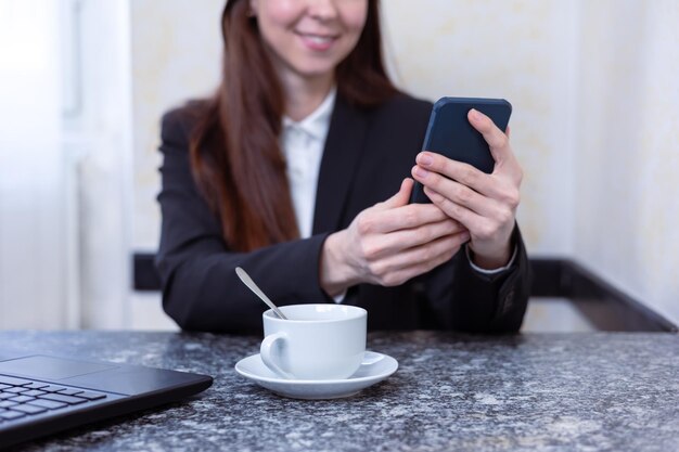 Mulher de negócios linda sorridente usando telefone celular para trabalhar no escritório