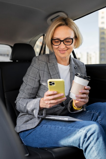 Foto mulher de negócios loira checando o telefone no carro