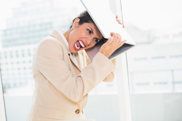 Mulher de negócios louca batendo na cabeça do laptop