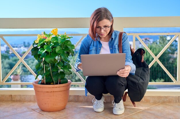 Mulher de negócios madura séria confiante com laptop ao ar livre