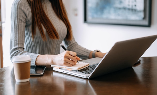 mulher de negócios mão trabalhando com um novo computador moderno e escrever no bloco de notas diagrama de estratégia como conceito de luz da manhã