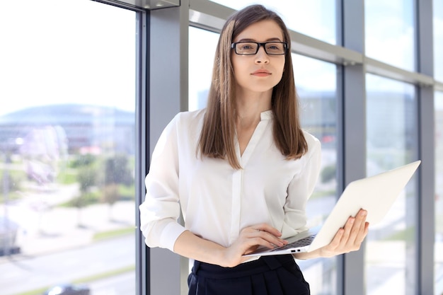 Mulher de negócios moderna digitando no laptop enquanto está no escritório antes da reunião ou apresentação