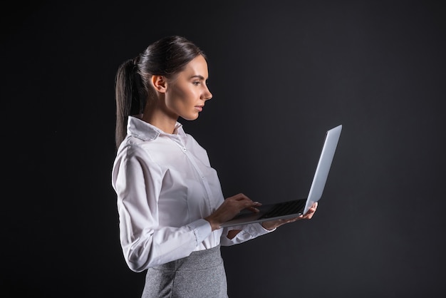 Mulher de negócios moderna. Mulher bonita e atraente segurando um laptop e trabalhando nele enquanto faz negócios