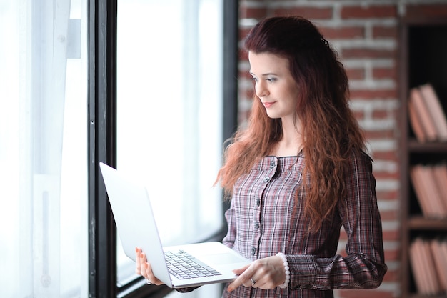 Mulher de negócios moderna usando laptop de pé no escritório