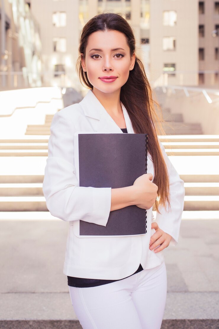 Mulher de negócios morena linda em um terno branco com pasta de documentos nas mãos ao ar livre