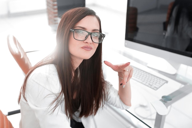 Mulher de negócios mostrando um gesto de diferença sentado atrás de uma mesa