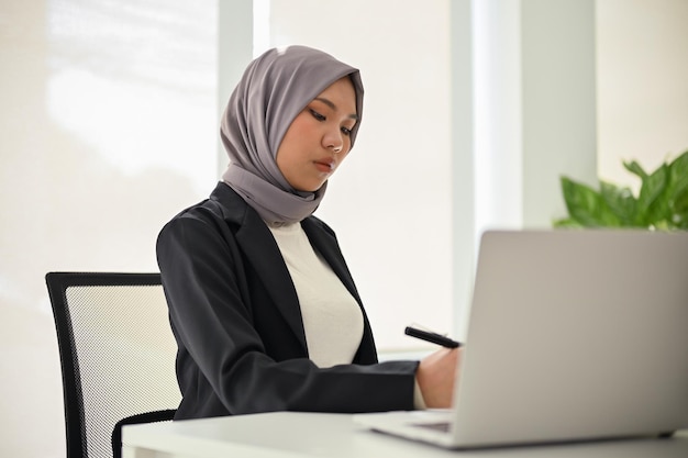Mulher de negócios muçulmana asiática profissional concentrando-se em suas tarefas de negócios trabalhando no escritório