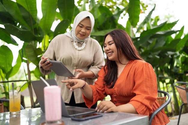 Mulher de negócios muçulmana discute sobre o trabalho com seu colega de trabalho em um café ao ar livre