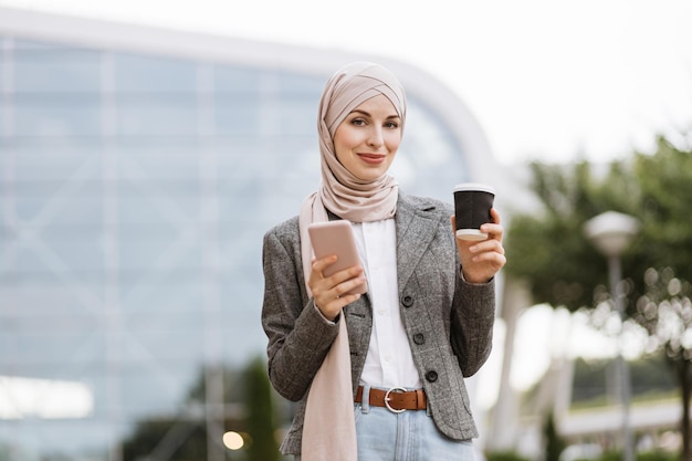 Mulher de negócios muçulmana em hijab em frente ao edifício moderno ou aeroporto