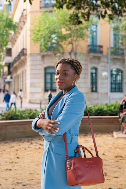 Mulher de negócios negra olha para a câmera enquanto ela está parada em um parque de uma cidade