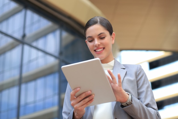 Mulher de negócios no trabalho com um tablet perto do escritório ao ar livre.