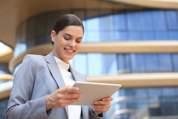 Mulher de negócios no trabalho com um tablet perto do escritório ao ar livre.