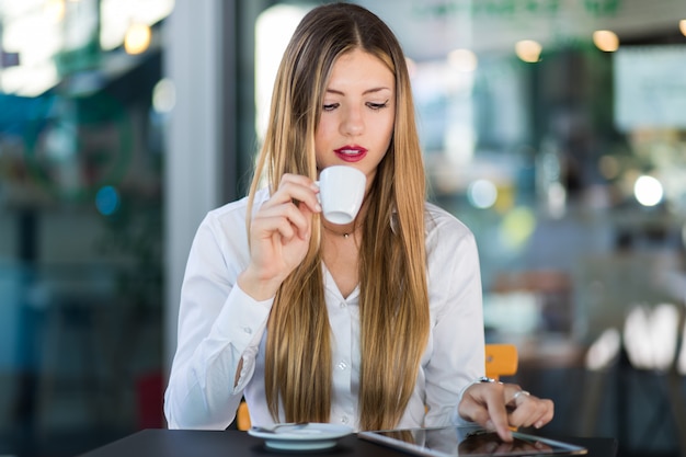 Mulher de negócios nova em uma ruptura de café Usando o computador tablet.