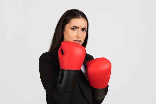 Mulher de negócios preocupada com luvas de boxe vermelhas.