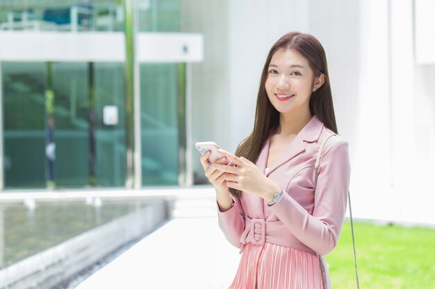 Mulher de negócios profissional asiática com cabelo comprido sorrindo na frente do escritório