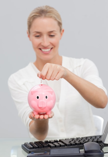 Mulher de negócios que poupa dinheiro em um piggibank