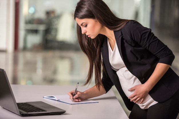 Mulher de negócios que trabalha em seu lugar de funcionamento no escritório.