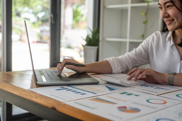 Mulher de negócios que trabalha o investimento financeiro na calculadora e no computador portátil